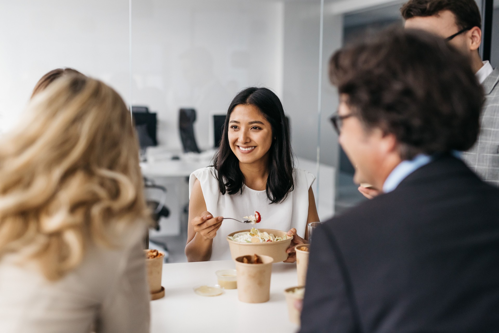 Smiling pretty woman enjoying takeaway lunch at work